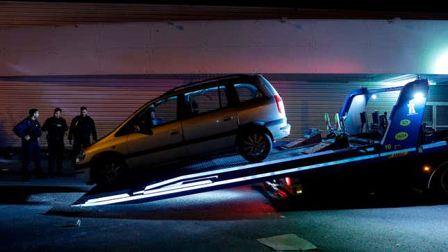 A broken down car is loaded onto a truck. 