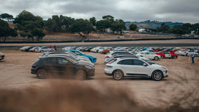 A group of Porsche Macans are parked on dirt at Laguna Seca raceway