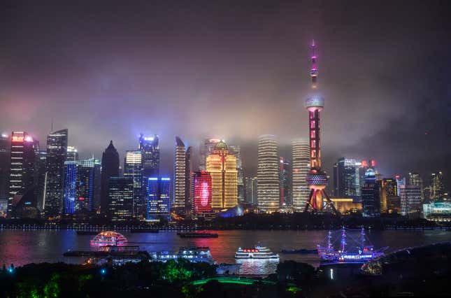 boats travel on the Huangpu River as the skyline of the city is is seen, including the Oriental Pearl TV Tower and the Shanghai Tower