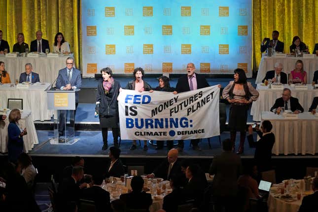 Climate activists step on stage with a banner before Federal Reserve Chairman Jerome Powell speaks at a meeting of the Economic Club of New York, Thursday, Oct. 19, 2023, in New York. (AP Photo/Seth Wenig)