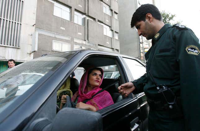 A policeman asks a woman wearing bright coloured clothes for her identification papers at a morals police checkpoint in Tehran June 16, 2008.