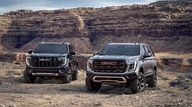 A side by side of the Yukon AT4 and Denali trucks parked on rocks in front of a plateau