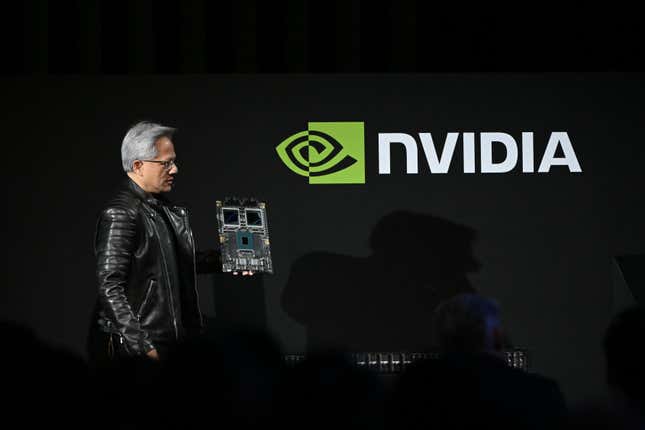 Jensen Huang holding a chip platform in front of a black backdrop with the Nvidia logo