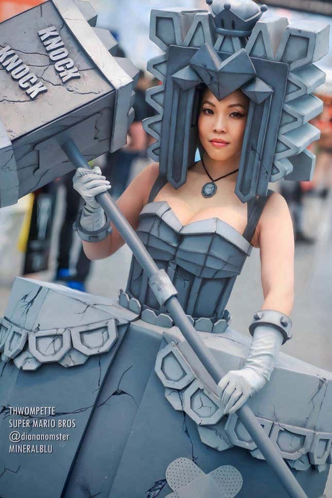A cosplayer wields a mallet and wears an all-grey, blocky outfit.