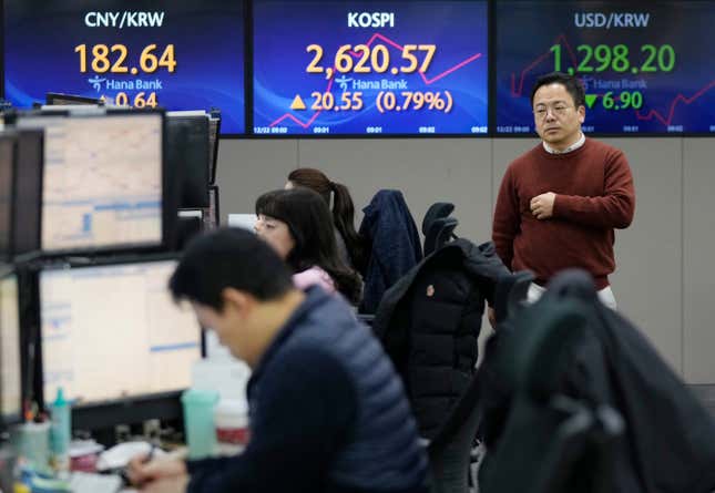 A currency trader passes by the screens showing the Korea Composite Stock Price Index (KOSPI), center, and the foreign exchange rate between U.S. dollar and South Korean won, right, at the foreign exchange dealing room of the KEB Hana Bank headquarters in Seoul, South Korea, Friday, Dec. 22, 2023. Shares were mostly higher in Asia on Friday after several strong profit reports helped Wall Street claw back most of its sharp loss from day before. (AP Photo/Ahn Young-joon)