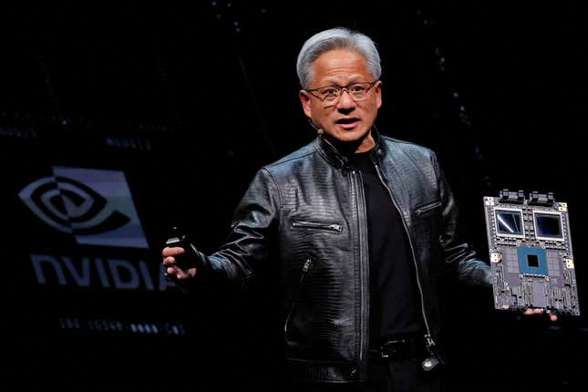 Jensen Huang wearing a black leather jacket, talking and holding a motherboard