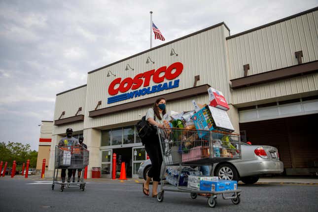 Shoppers with full shopping carts leave a Costco store