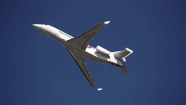 A photo of a white private jet taking off from an airport. 