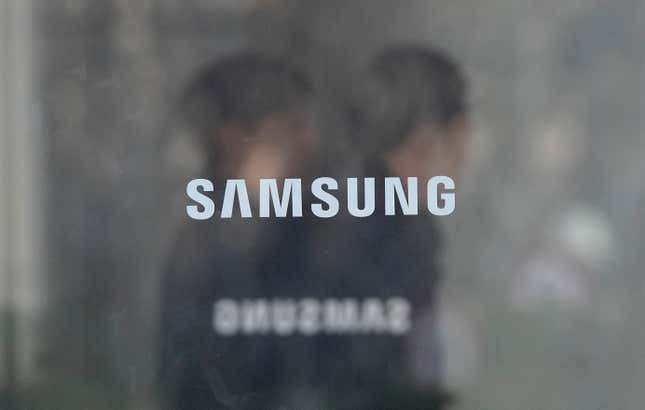 Employees walk past logos of the Samsung Electronics Co. at its office in Seoul, South Korea, Wednesday, Jan. 31, 2024. Samsung Electronics on Wednesday reported an annual 34% decline in operating profit for the last quarter as sluggish demands for its TVs and other consumer electronics products offset hard-won gains from a slowly recovering computer chip market. (AP Photo/Ahn Young-joon)