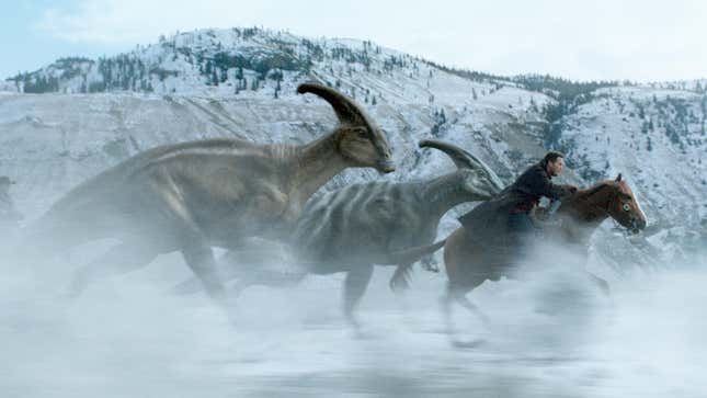 Chris Pratt on a horse riding with dinosaurs against a snowy backdrop.