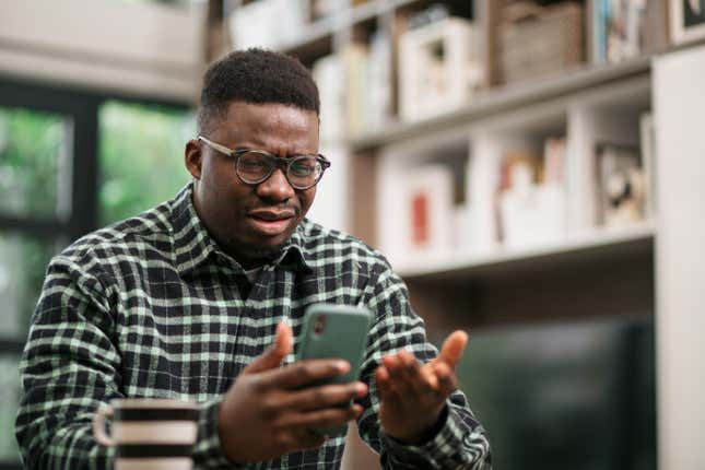 Black man looking confused at his phone. 