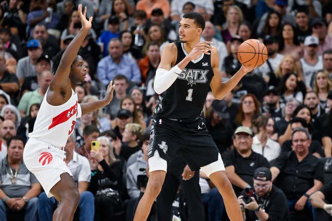 San Antonio Spurs&#39; Victor Wembanyama (1) looks to pass the ball as he is defended by Toronto Raptors&#39; O.G. Anunoby, left, during the second half of an NBA basketball game, Sunday, Nov. 5, 2023, in San Antonio. (AP Photo/Darren Abate)