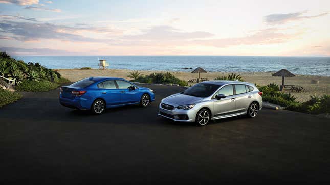 A blue Subaru Impreza sedan and silver hatchback on a beach