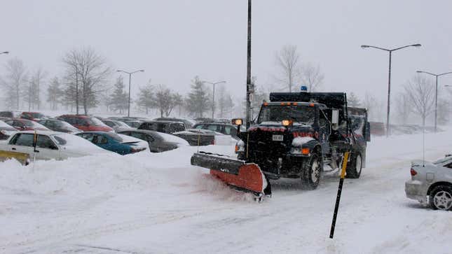 un chasse-neige circulant sur un parking enneigé