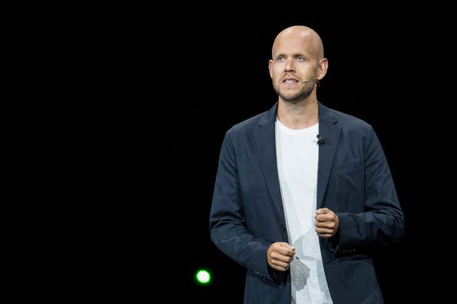 Daniel Ek wearing a white t shirt and navy suit jacket speaking on stage