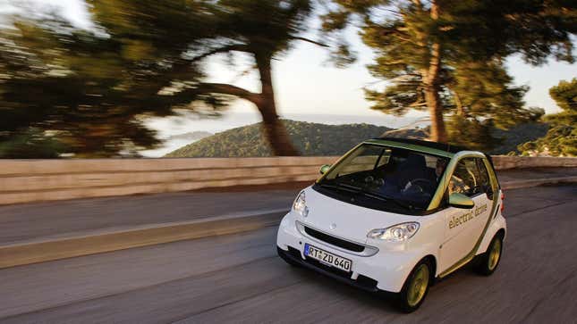 Ein weiß und grüner ForTwo ED fährt auf einer kurvigen Straße zwischen Bäumen