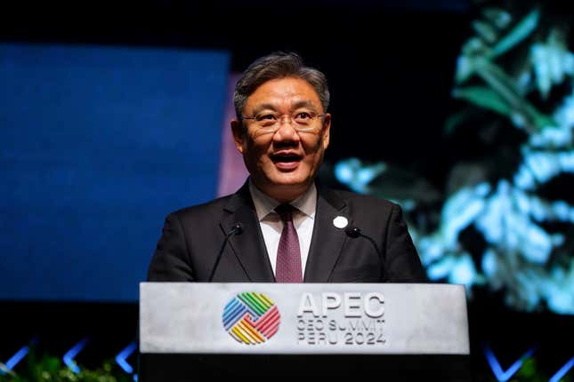 Weng Wentao speaking at a podium with the APEC symbol