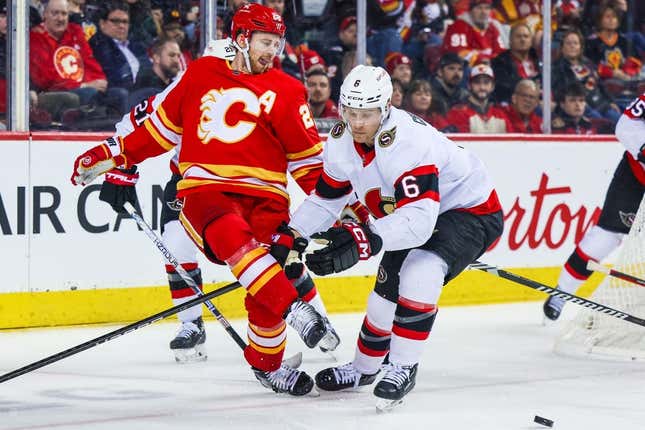 9. Januar 2024;  Calgary, Alberta, CAN;  Calgary Flames Center Elias Lindholm (28) spielt den Puck mit seinem Schlittschuh gegen Jakob Chychrun (6), den Verteidiger der Ottawa Senators, während der zweiten Periode im Scotiabank Saddledome.