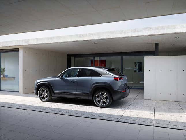 A Mazda MX-30 parked in front of a modern minimalist home