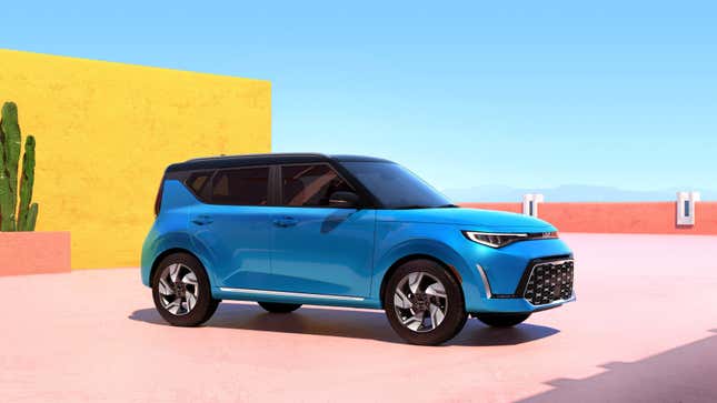 A blue Kia Soul parked near a colorful desert-style building