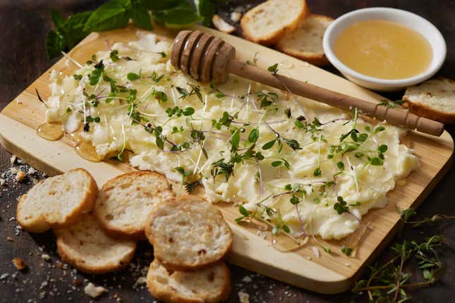 A butter charcuterie board with fresh herbs.