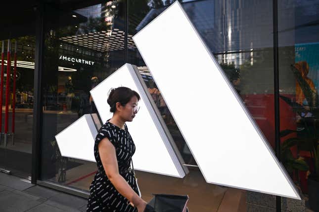 Une femme passe devant un magasin Adidas dans un centre commercial