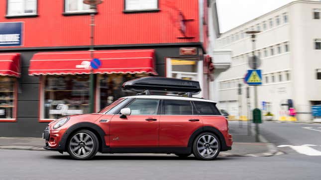 une mini-clubman rouge qui file dans un virage avec un coffre de toit