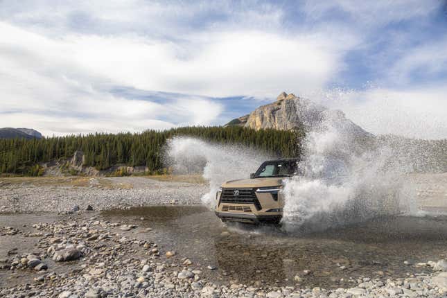 A beige Lexus GX 550 splashing through a puddle