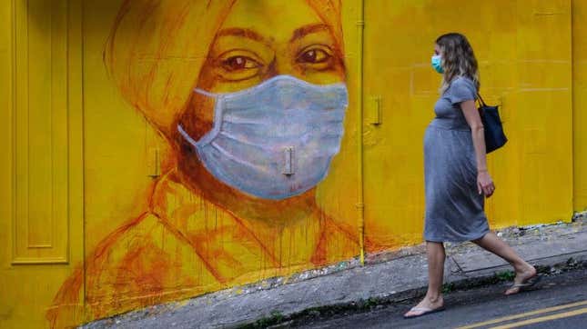  A pregnant woman walks past a street mural in Hong Kong on March 23, 2020.