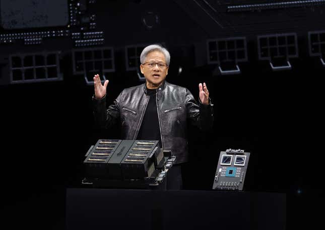 Jensen Huang standing behind two chip platforms with his arms raised as he's talking