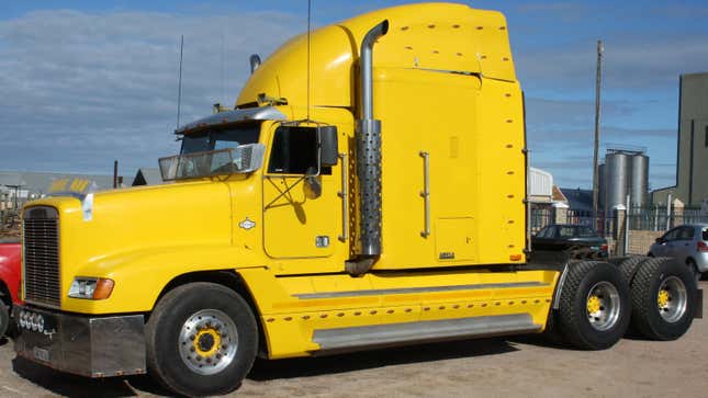 A yellow Freightliner FLD 120 from the side showing its Mercedes turn indicators