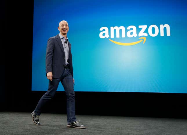 Jeff Bezos walks onto the stage, behind him is a blue backdrop with the Amazon logo