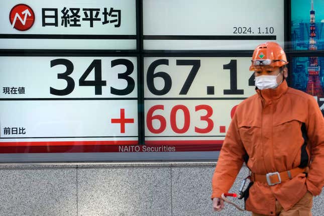 A worker walks past an electronic stock board showing Japan&#39;s Nikkei 225 index at a securities firm Wednesday, Jan. 10, 2024 in Tokyo. (AP Photo/Shuji Kajiyama)