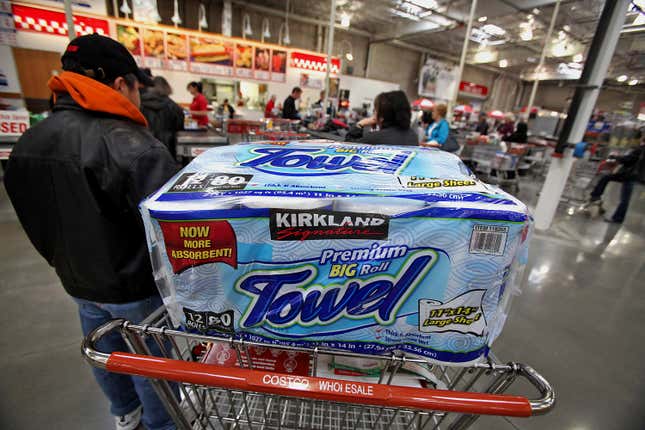 A package of Kirkland Signature brand paper towels sits in a customer’s shopping cart while he waits to check out a Costco.