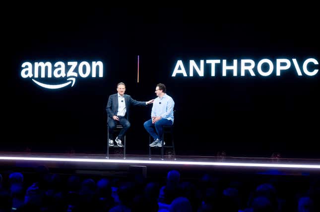 Adam Selipsky y Dario Amodei se sientan en taburetes en el escenario frente a los logotipos de Amazon y Anthropic