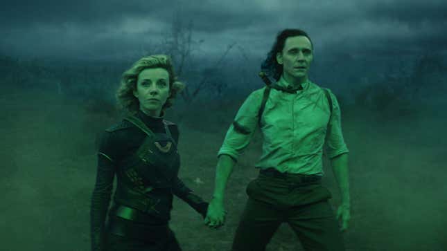 Loki (Sophia Di Martino) and Loki (Tom Hiddleston) hold hands while bathed in green light.