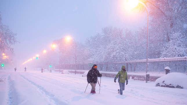 People walk amid a heavy snowfall in Madrid on January 9, 2021.
