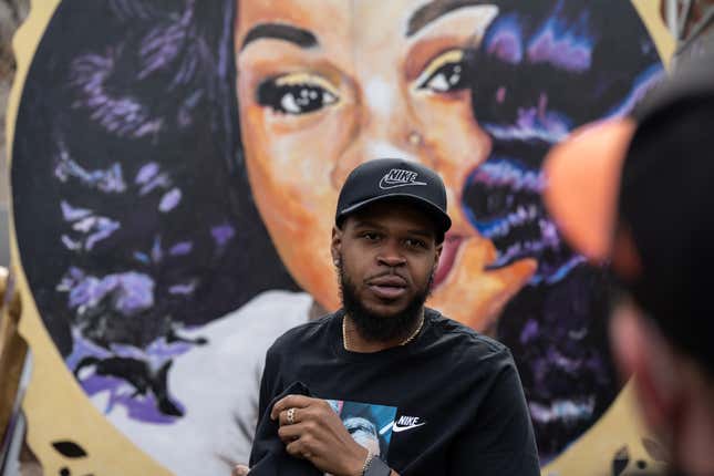 Kenneth Walker, boyfriend of Breonna Taylor, stands in front of a portrait of Taylor during a protest memorial for her in Jefferson Square Park on March 13, 2021 in Louisville, Kentucky. Today marks the one year anniversary since Taylor was killed in her apartment during a botched no-knock raid executed by LMPD.