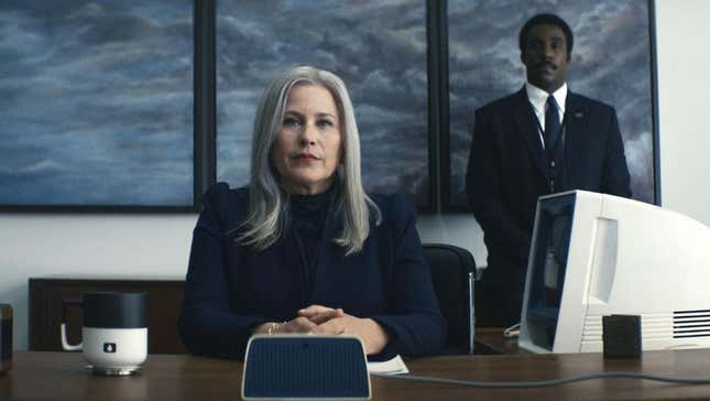 Cobel sits at her desk as Mr. Milcheck stands behind her.