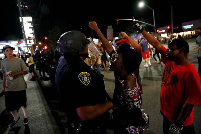 A woman protests in the face of a police officer as people protest the death of Alfred Olango, by blocking traffic near the parking lot where Olango was shot in El Cajon, California, U.S.
