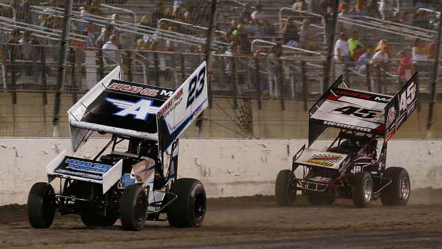 A photo of two dirt cars racing on a track. 