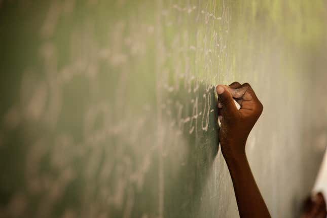 Black kid writing on chalk board 