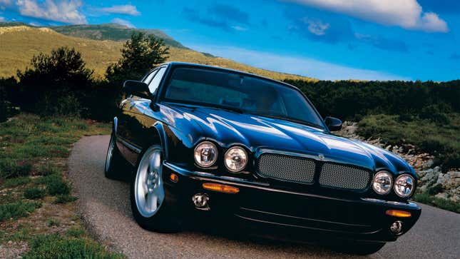 A black Jaguar XJ sedan driving in the countryside. 