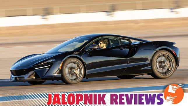 A black McLaren Artura being driven on a racetrack.