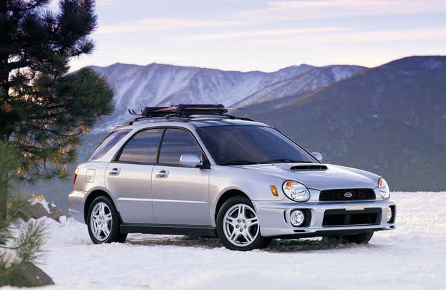 Front quarter view of a silver Subaru Impreza WRX wagon parked on snow in the mountains.