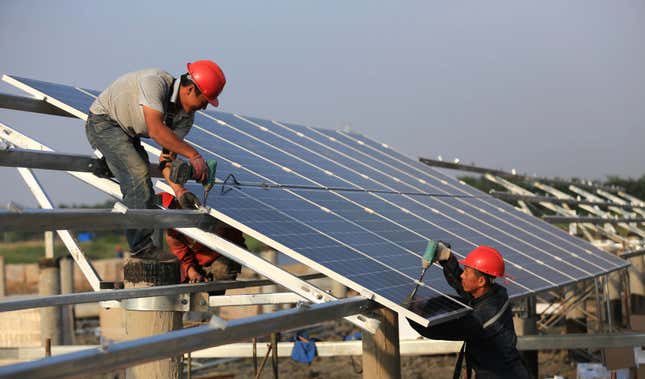 Workers install solar panels at the construction site in China.