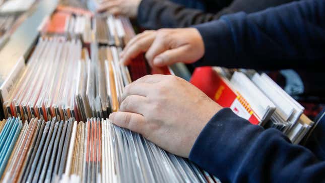 A pair of hands peruses the vinyl selection in a record store.