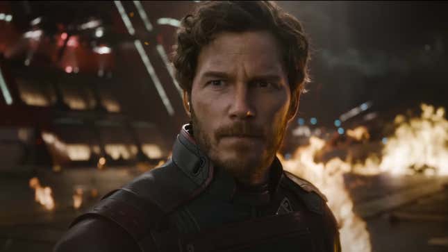 Star-Lord looking at something off-screen as fire burns behind him.