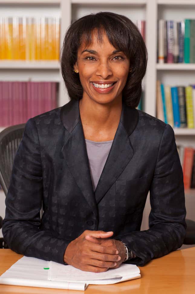 Labor economist and Princeton dean Cecilia Rouse smiles and sits at at desk in front of bookcases in a black blazer.