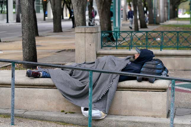 FILE - A man lies in a park covered with a blanket against the cold, Saturday, Jan. 29, 2022, in Miami. Florida’s homeless will be banned from sleeping in public spaces such as sidewalks and parks under a law signed Wednesday, March 20, 2024, by Republican Gov. Ron DeSantis. (AP Photo/Lynne Sladky, File)